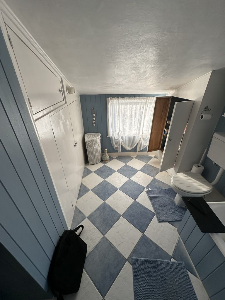 Original family bathroom Braintree CM7 before renovation showing blue and white checkerboard floor with panelled walls