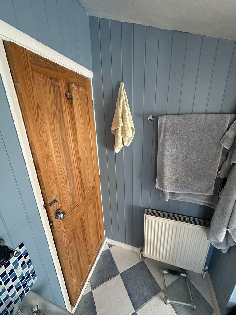 Original family bathroom Braintree CM7 before renovation showing wood door and radiator corner view